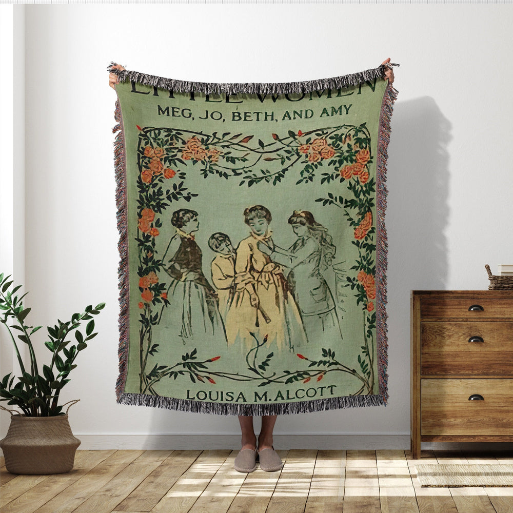 Little Women woven throw blanket showing the vintage cover with Meg, Jo, Beth, and Amy under a rose garland