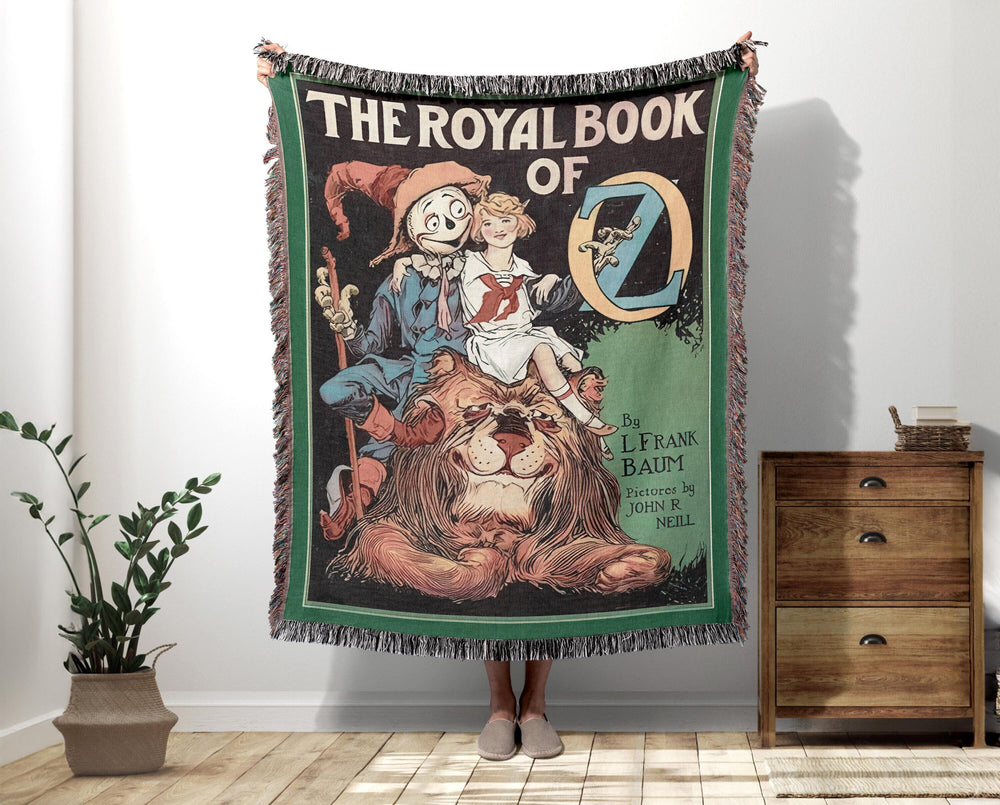 The Royal Book of Oz woven throw blanket showing the vintage cover with Dorothy, the Scarecrow, and the Cowardly Lion