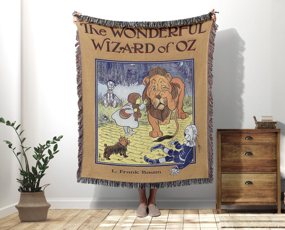 Wizard of Oz woven throw blanket showing Dorothy, Toto, the Cowardly Lion, Scarecrow, and Tin Man in classic storybook art